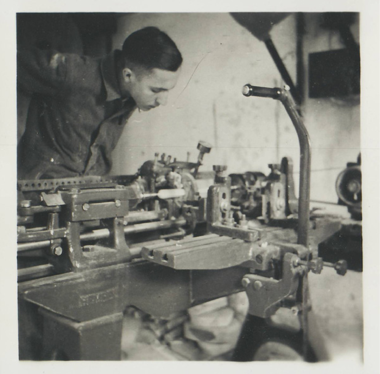 Historische Aufnahme aus den 1930er-Jahren: Ein Drechsler arbeitet konzentriert an einem mechanischen Dreh-Halbautomaten in einer traditionellen Werkstatt.